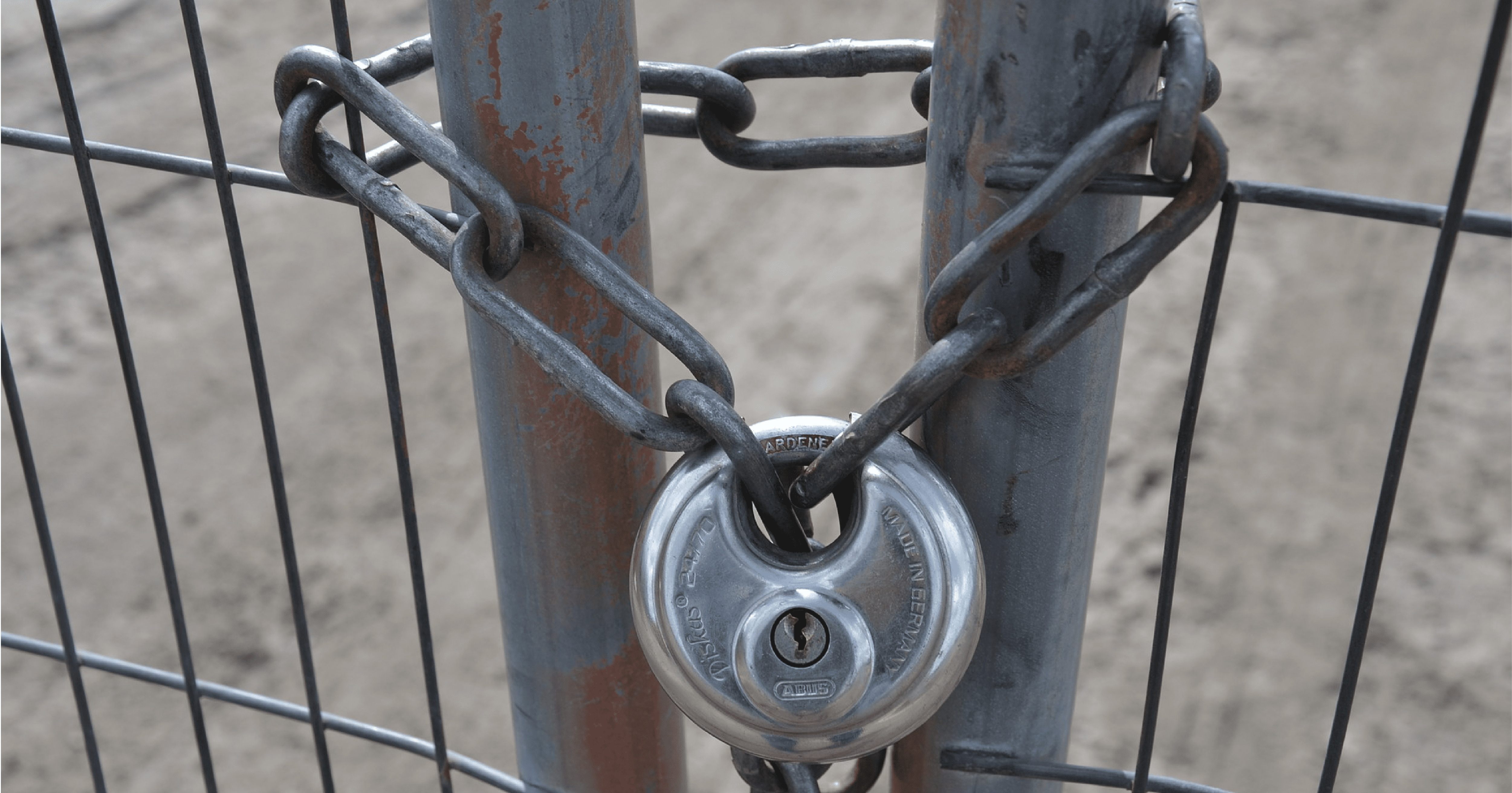 Un eslabón de cadena enrollado a través de una cerca y asegurado por un candado