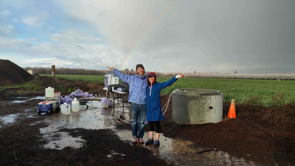 Christine He en un campo con un arco iris