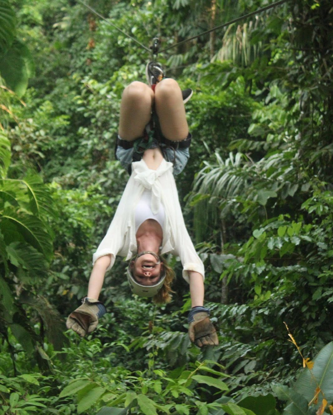Kelsey Hern hanging upside down, zip lining in Costa Rica