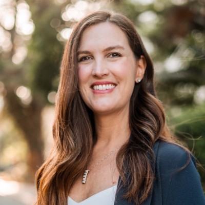 Kelly Quigley, a white woman with long brown hair, smiling in a cardigan