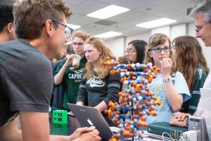 Students standing behind a toy model of DNA