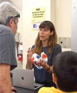 Scientist holding a 3D printed model of a protein and talking