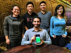 Michael Gomez holding a cell phone with four people behind him