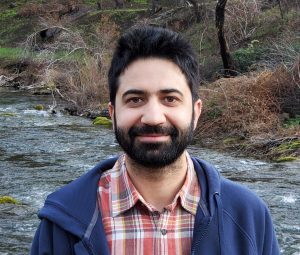 Imtiyaz Khanday, a Kashmiri man, stands in front of a stream