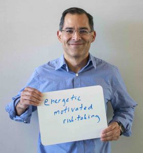 David Schaffer holding a whiteboard with three words written on it