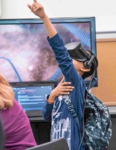 Child pointing upwards with a virtual reality headset on