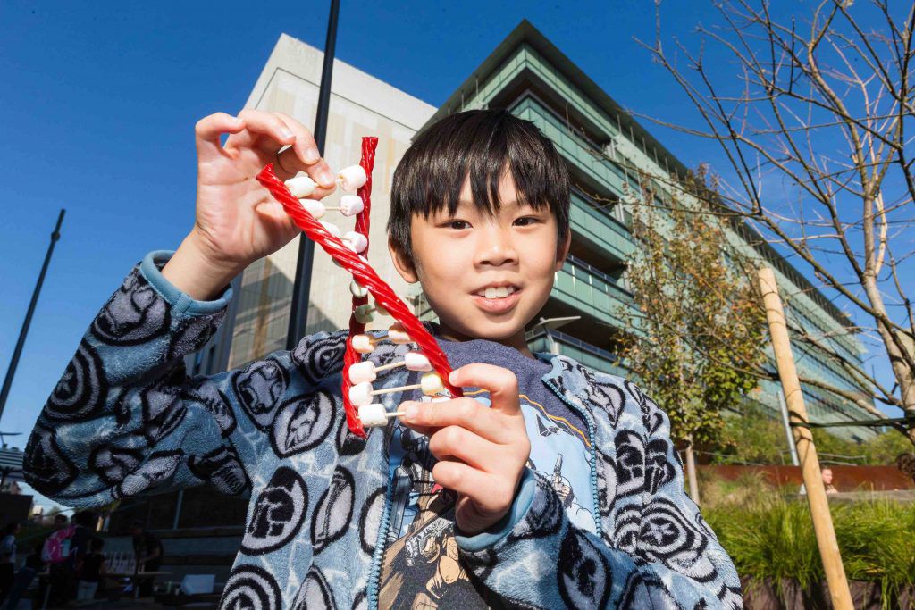 photo of a child holding a candy model of DNA