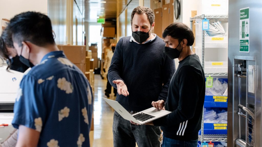 Alex Marson (center) and his colleagues created the most detailed map yet of how complex networks of genes function together. Seen here speaking with Ujjwal Rathore, staff research scientist at Gladstone.