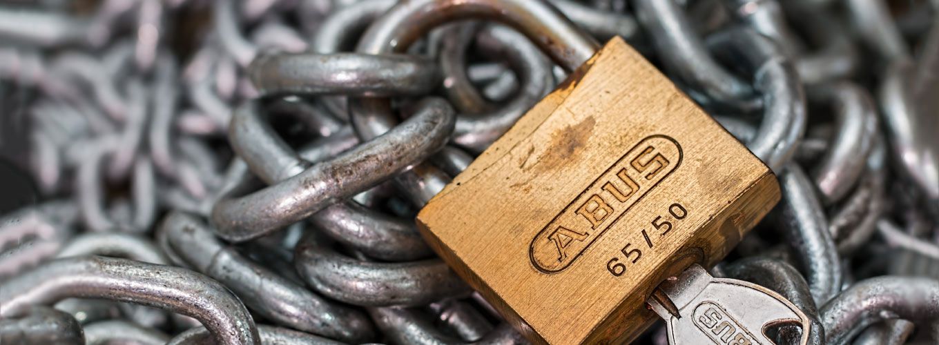 A padlock and key sitting on chains