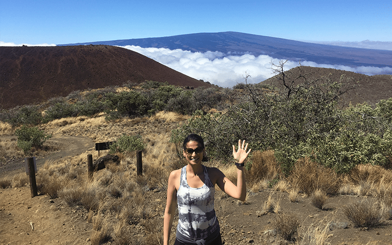 Shaheen Kabir waving during a hike with a beautiful landscape in the background