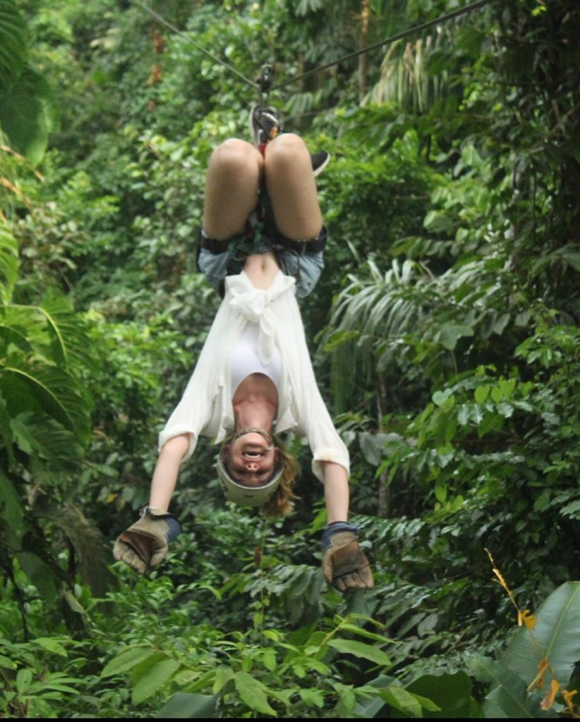 Kelsey Hern hanging upside down, zip lining in Costa Rica