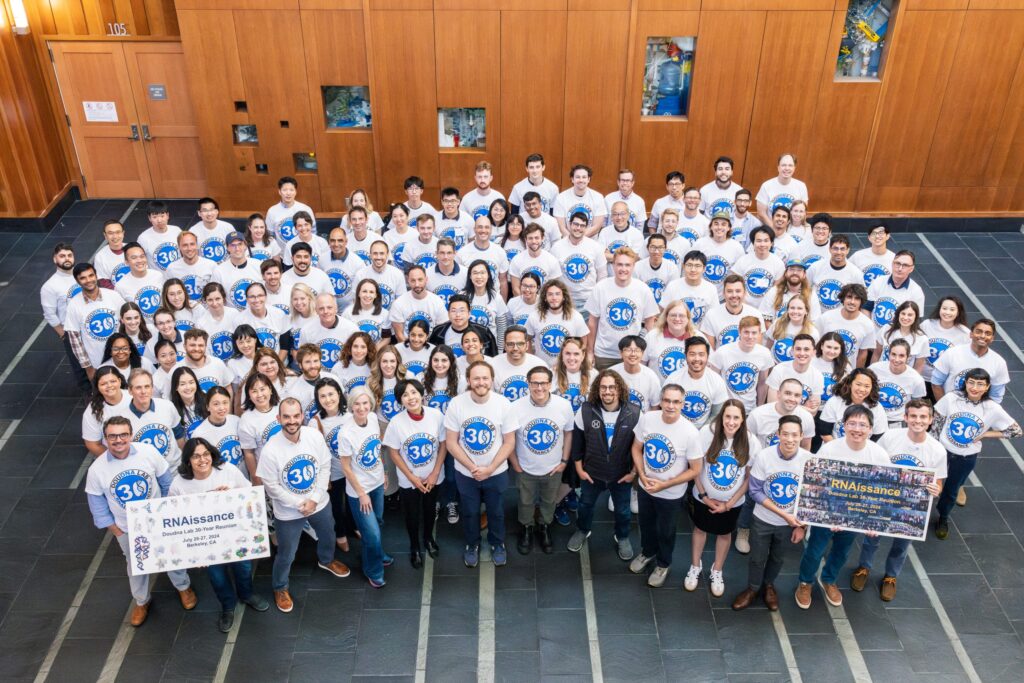 Doudna Lab reunion. A large group of people in white t-shirts looking at the camera.